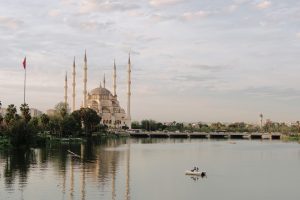 Scenic view of Sabancı Mosque and Seyhan River in Adana, Türkiye, featuring serene water reflection.